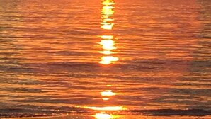 Ein Sonnenuntergang über einem ruhigen Meer mit klarem Horizont.