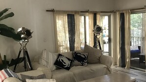 Ein Wohnzimmer mit einer Couch, einem Couchtisch und einem Stativ mit einer Kamera.