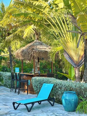 A lounge chair, a thatched-roof structure, and a large vase in a tropical setting. - You Know you want to be Here!/Sleeps 6/Private Pool and Fun Tiki Bar! (Providenciales)