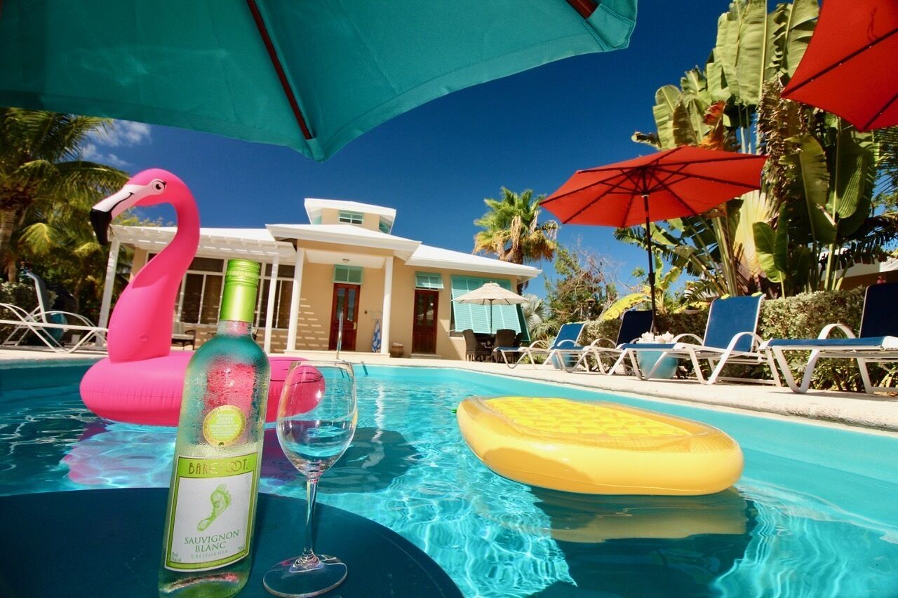 A pool area with a flamingo float, a bottle of wine, and a glass.