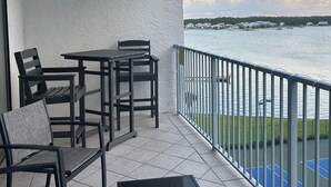 Un balcon avec une table et des chaises, une vue sur l’eau et une balustrade.
