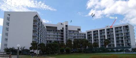 Un hotel moderno con varios pisos, vista al mar y cielo despejado.