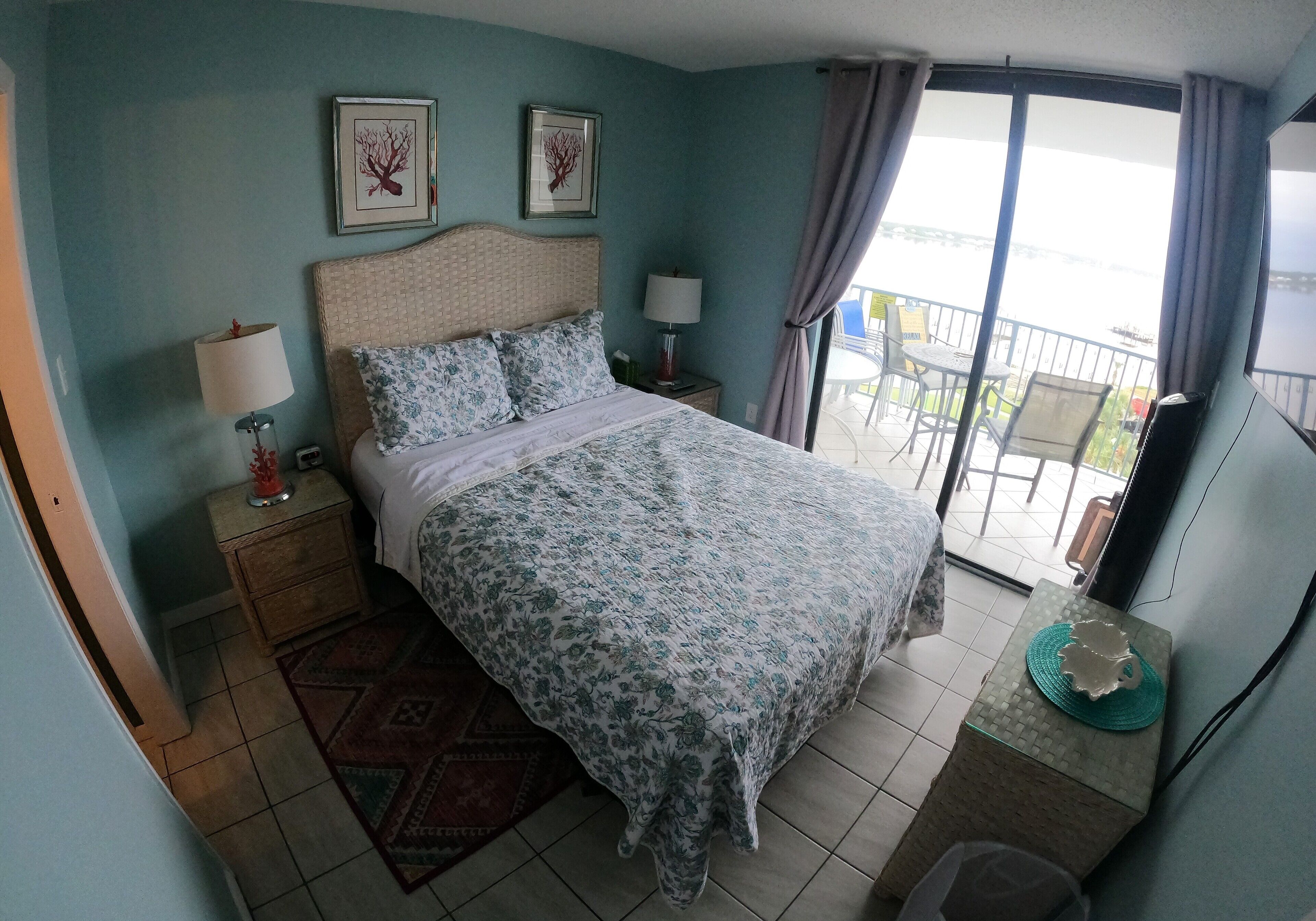 Ein Schlafzimmer mit Bett, Nachttischen, Schreibtisch und einem Balkon mit Blick.