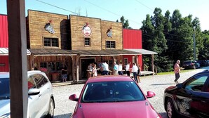 A red car parked in front of a building with a wooden facade and a red awning. - The Highlander Rustic Yurt (Genoa)