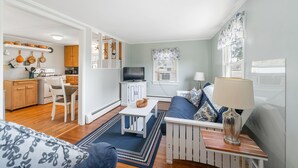 A compact living space with a kitchenette, a dining area, a sofa, and a TV.