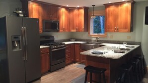 Eine moderne Küche mit Holzschränken, Edelstahlgeräten und einer Arbeitsplatte aus Granit.