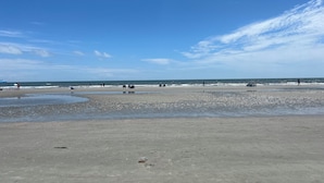 Une plage avec un rivage sablonneux, une mer calme et un ciel dégagé.