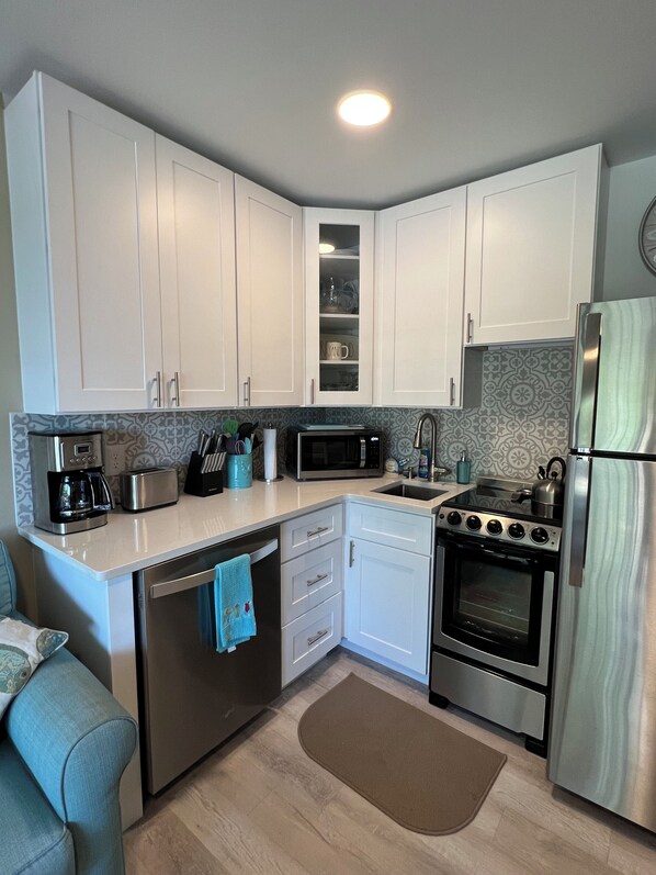 A modern kitchen with white cabinets, stainless steel appliances, a microwave, toaster, and a dishwasher. - AWESOME REMODEL! FREE BIKES, ALL BEACH GEAR, on the beach, 5-star reviews. (hilton head island)