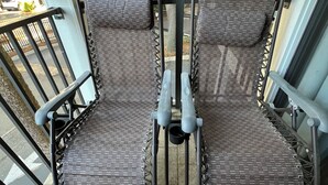 Deux chaises en osier avec des armatures en métal, sur une terrasse carrelée.