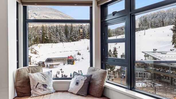 A window seat with a view of a snowy mountain and ski resort.