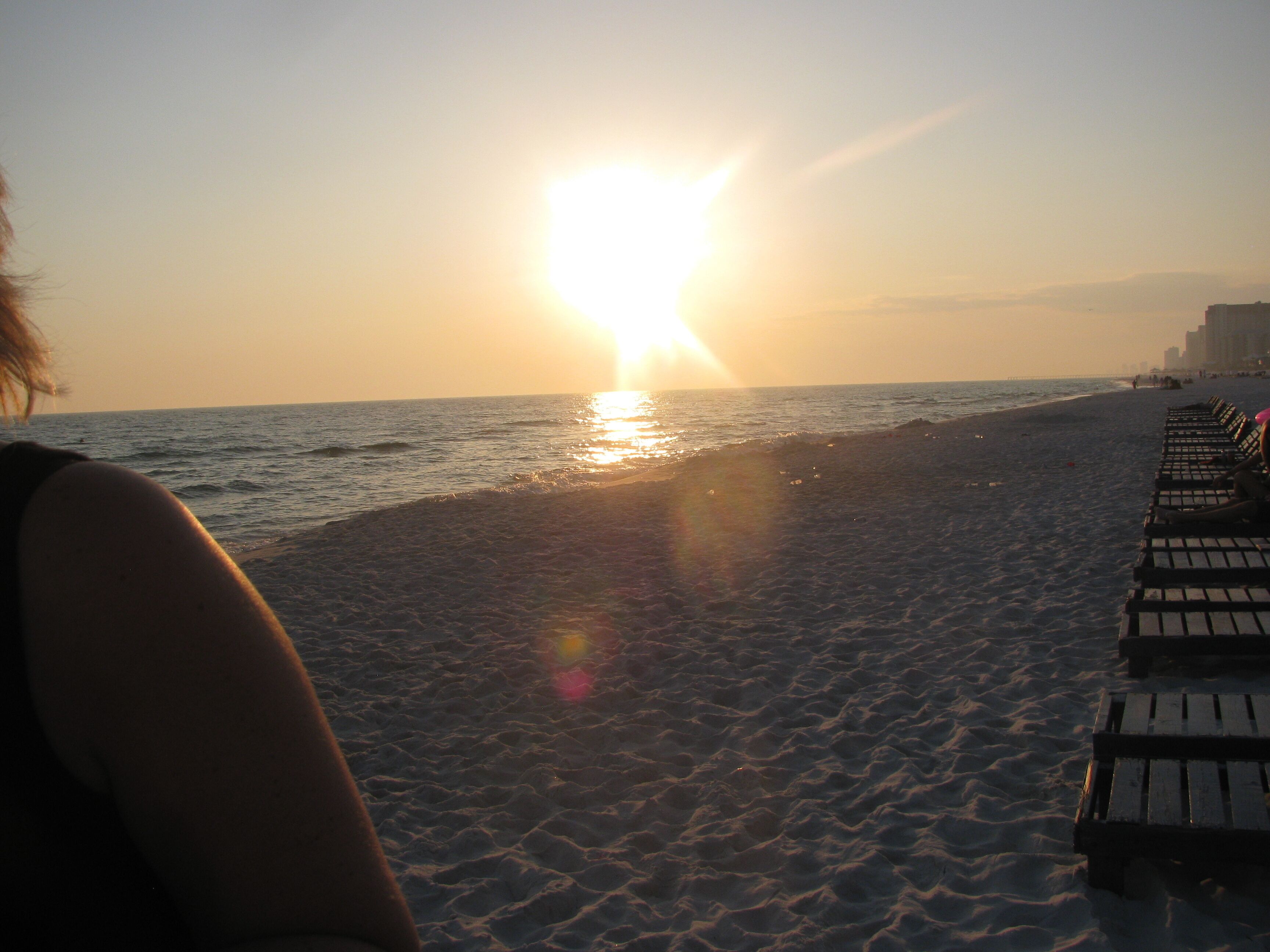 Ein Strand mit Holzbanken und einem Sonnenuntergang im Hintergrund.