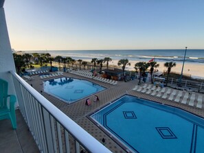 Un espace piscine comprenant deux piscines, un bar et une vue sur la plage.