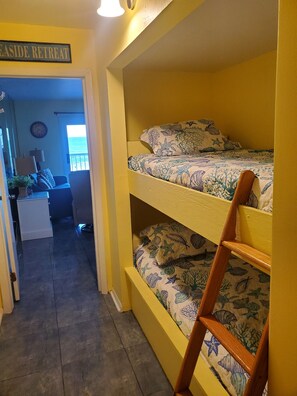 Une chambre avec un lit superposé, un bureau, une chaise, une lampe et une pancarte sur laquelle on peut lire : « EASIDE RETREAT ».