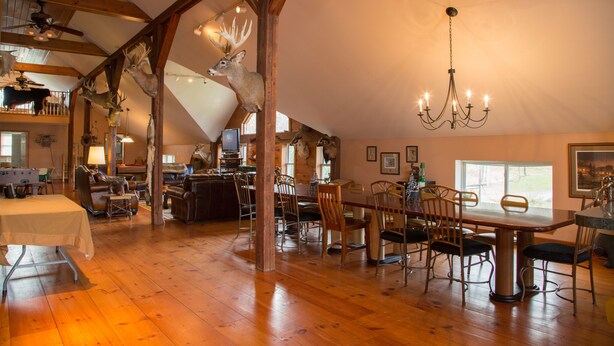 A spacious loft-style dining area with a high ceiling, wooden beams, and a chandelier. - Country Getaway Lodge/Ranch near Saratoga Springs (valley Falls)