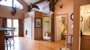 A room with wooden floors, a dining table with chairs, a fireplace, and mounted animal heads on the wall. - Country Getaway Lodge/Ranch near Saratoga Springs (valley Falls)