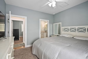 Un dormitorio con cama, cómoda y una puerta que da a un baño.