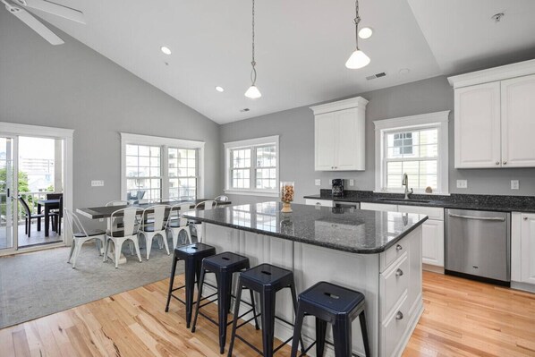 A modern kitchen with a large island, white cabinetry, and a dining area with bar stools.