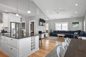 A modern kitchen with white cabinetry, a large island, and a dining area with a wooden table and chairs.