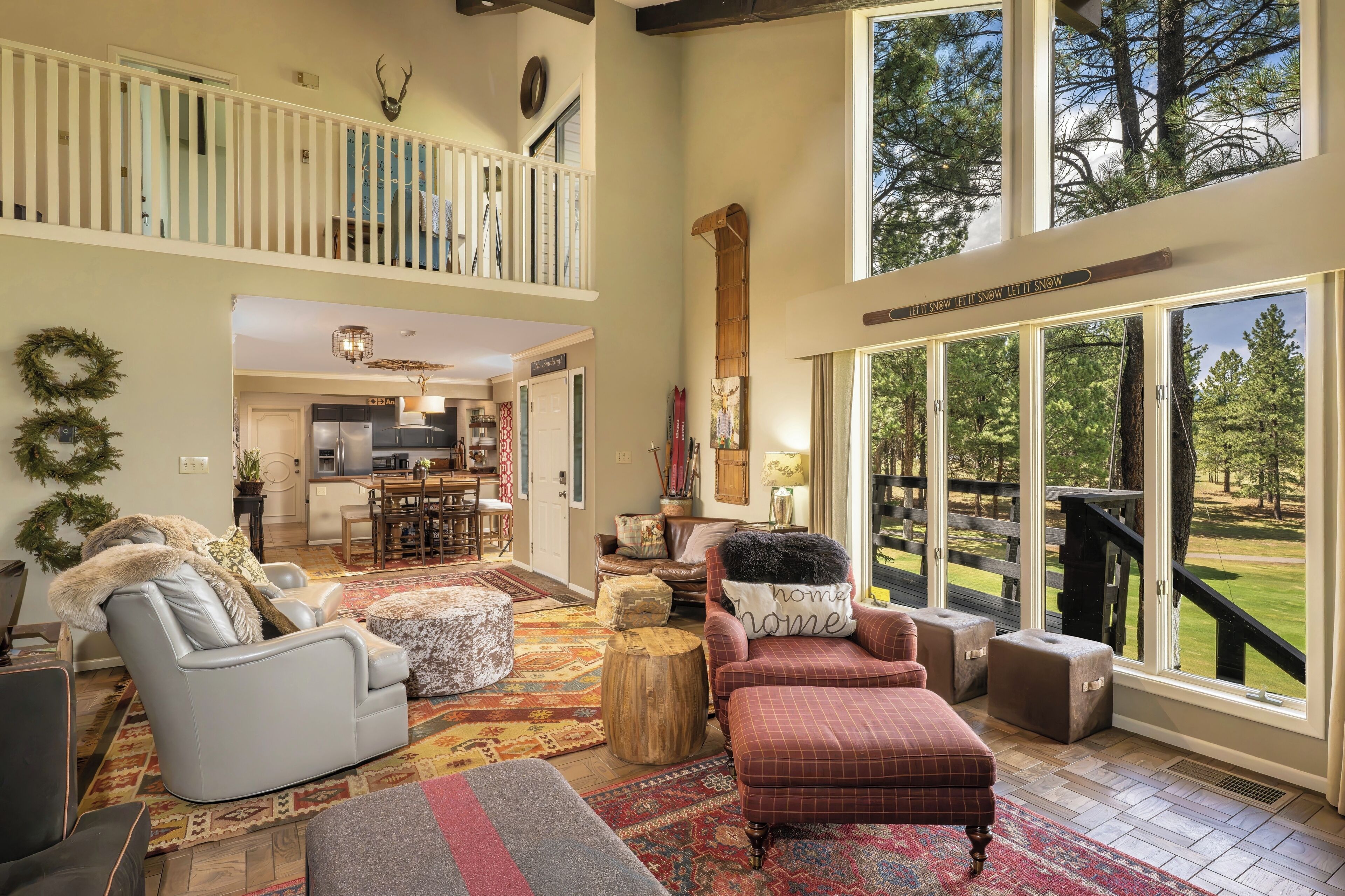 A spacious living area with a high ceiling, a dining area, and a view of a landscaped outdoor area.
