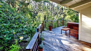 Une terrasse en bois avec une rambarde, des plantes en pot et du mobilier d’extérieur.