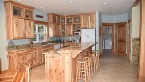 Una cocina amplia con armarios de madera, encimera de granito y una isla central con taburetes.