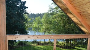 Una terraza de madera con vistas a un lago y bosque.