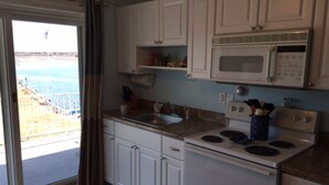 A kitchen with white cabinets, a microwave, a stove, and a sink. - Cozy Riverside Studio Condo Two Minute Walk To Wells Beach
 (Wells)
