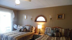 A room with two beds, a nightstand with a lamp, a wall-mounted clock, and a window with curtains. - Room 3 at Otter Creek Inn (Mt Desert)