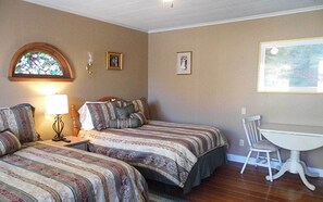 A bedroom with two beds, a nightstand, a lamp, a chair, and a small table. - Room 3 at Otter Creek Inn (Mt Desert)