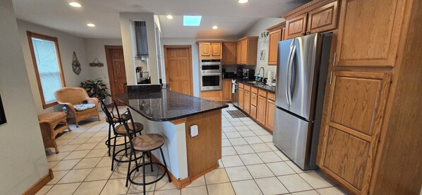 A kitchen with wooden cabinets, a stainless steel refrigerator, and a bar stool area.