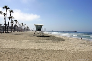 Enjoy a serene beach experience with a lifeguard tower and pier, surrounded by palm trees.
