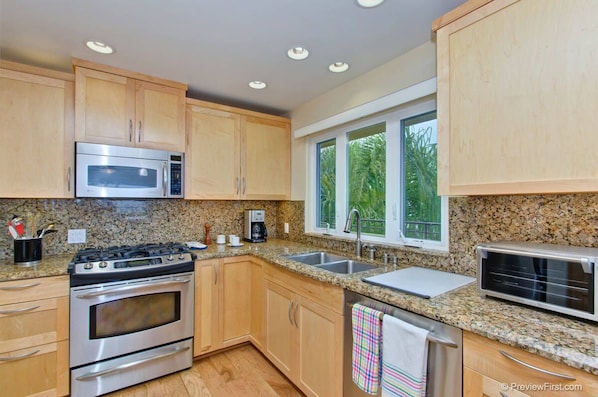 Enjoy cooking in this well-equipped kitchen with a microwave, stove, and toaster, and take in the view of the surrounding greenery.