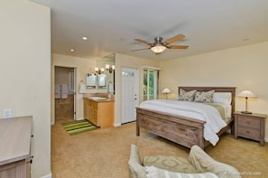 Cozy retreat with a large bed, nightstand, and lamp, plus a ceiling fan and mirror.