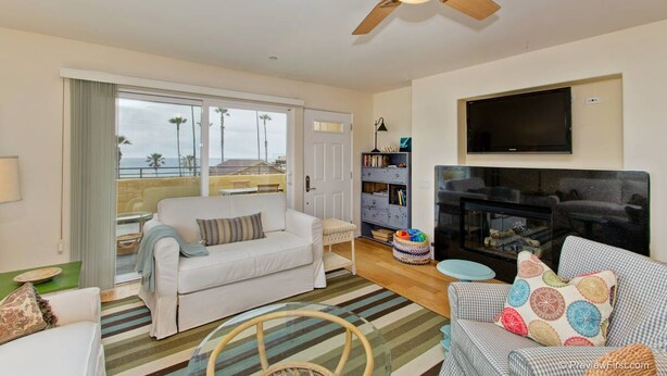 A living room with a sofa, a television, a fireplace, and a bookshelf. - OCEAN VIEWS!!!! Penthouse located across the street to beach!! (Oceanside)