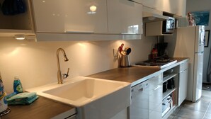 A modern kitchen with white cabinets, a stainless steel sink, a microwave, and a stove.