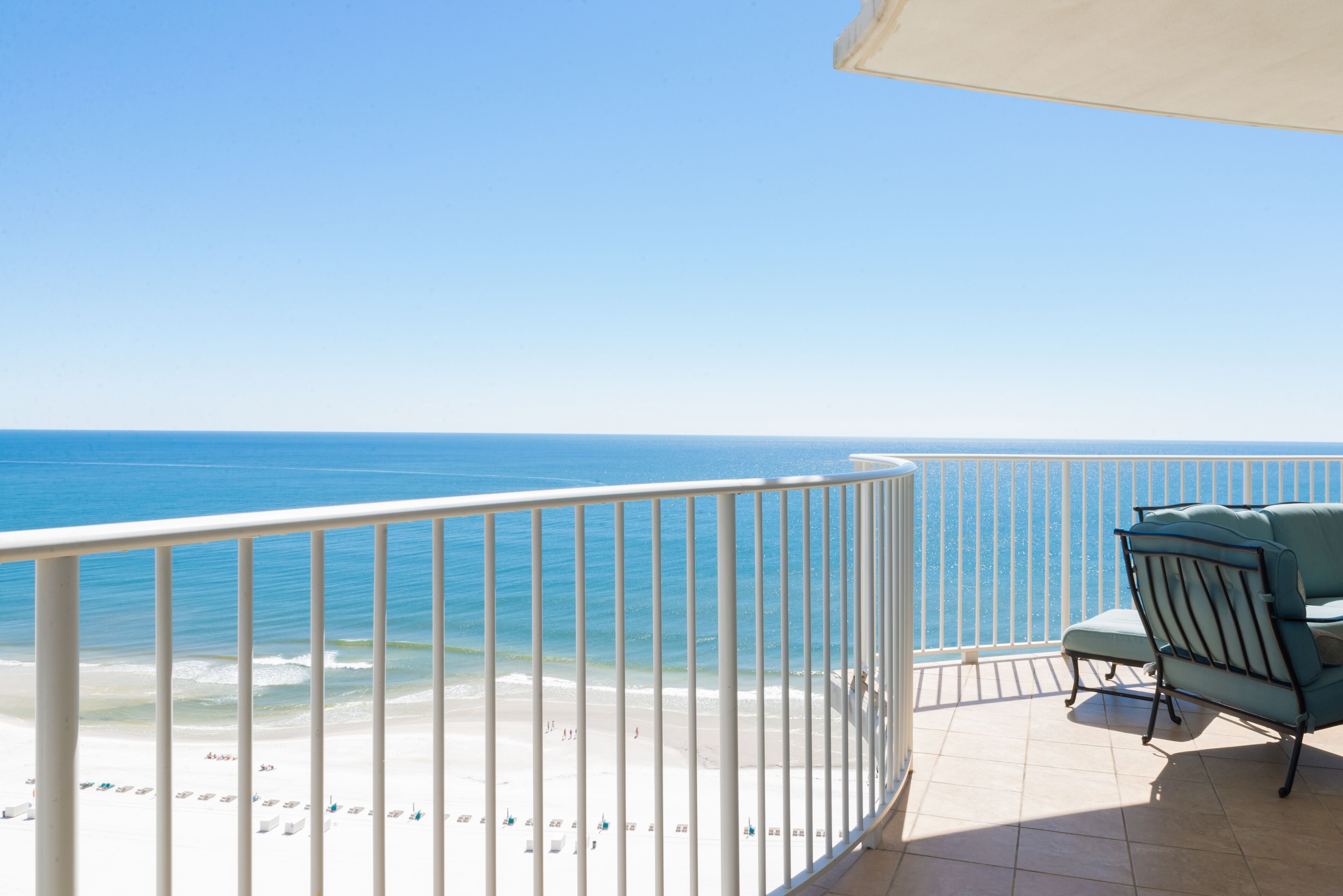A balcony with a view of the beach and ocean.