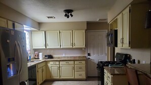 A kitchen with light-colored cabinets, a refrigerator, a microwave, and a stove. - Pet-friendly, Family-friendly & Fun-Friendly Central-to-Everything Phoenix Home (Phoenix)