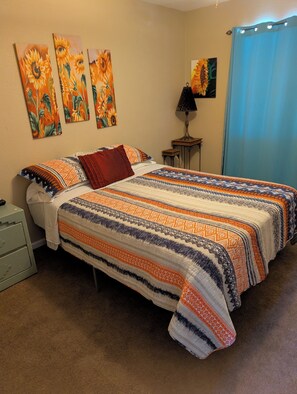 A bedroom with a bed, a nightstand, a lamp, and wall art.