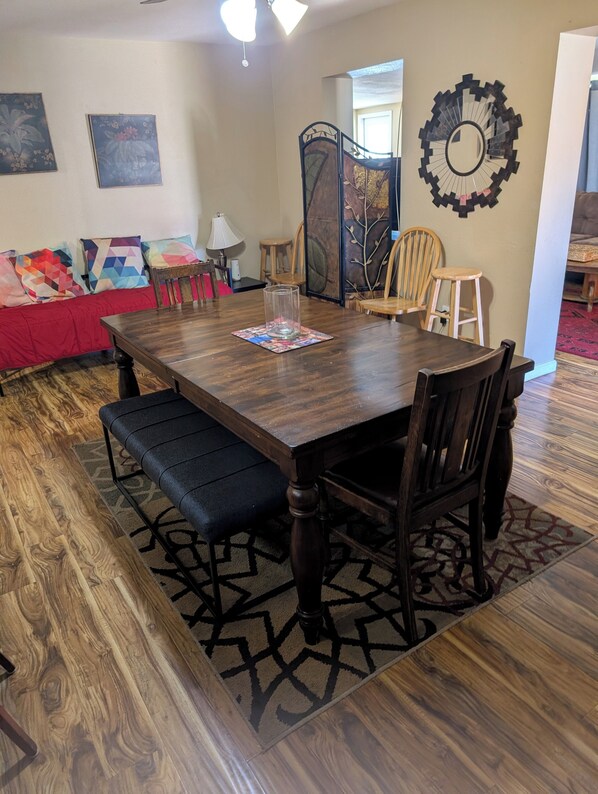 A dining area with a wooden table, chairs, a bench, and a patterned rug.