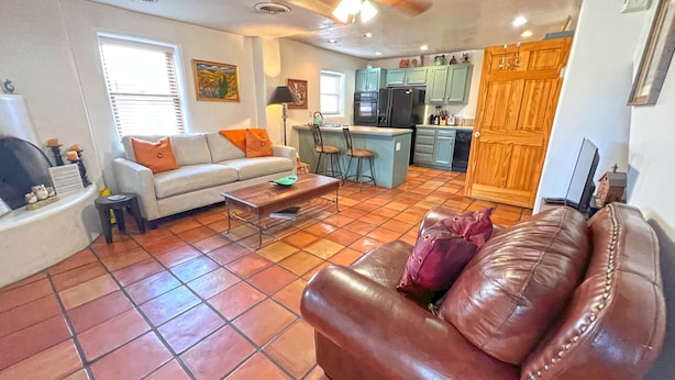 A living room with a sofa, coffee table, and a dining area with chairs and a kitchen in the background. - Casita F - 2 Bed, 1.5 Bath (Two Story) (Santa Fe)