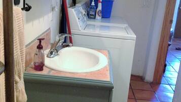 A compact bathroom with a sink, mirror, and a washing machine.