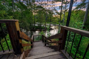 Un escalier en bois descend vers une rivière bordée d’une forêt dense.