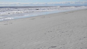 A beach with a wide sandy shore and waves crashing onto the beach.