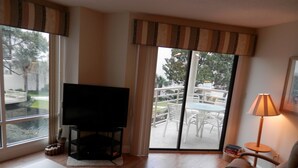 A living room with a flat-screen TV, a sofa, a table, and a lamp.