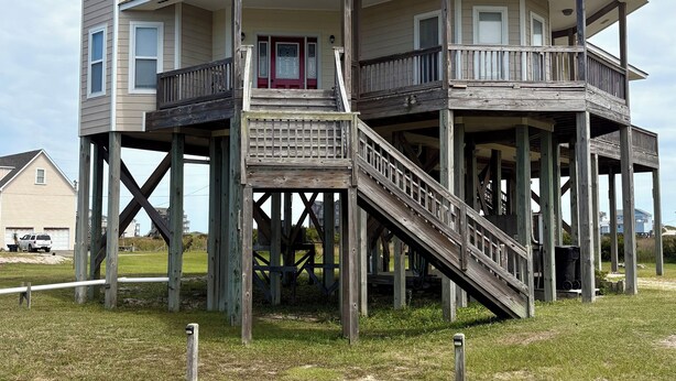 Ein zweistöckiges Haus mit einem Balkon und einer Holztreppe.