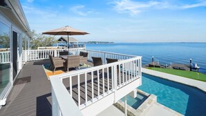 Terraza con mobiliario exterior y piscina con vista a un cuerpo de agua.
