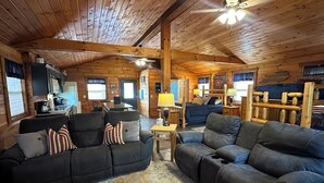 A cozy log cabin interior with a living room featuring two dark sofas, a coffee table, and a ceiling fan. - Cozy Cabin center of Bourbon Trail, Near Bardstown, beautiful country views (Springfield)