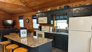 A kitchen with granite countertops, wooden stools, a refrigerator, a microwave, and a coffee maker. - Cozy Cabin center of Bourbon Trail, Near Bardstown, beautiful country views (Springfield)