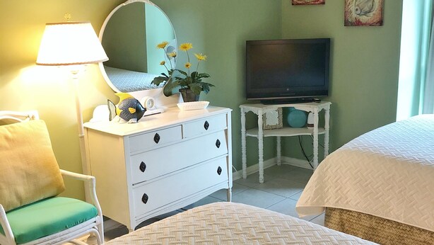 A hotel room with a bed, a dresser, a chair, a television, and a mirror.
