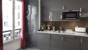 Une cuisine moderne avec des meubles gris, un four à micro-ondes encastré et un évier en acier inoxydable.
